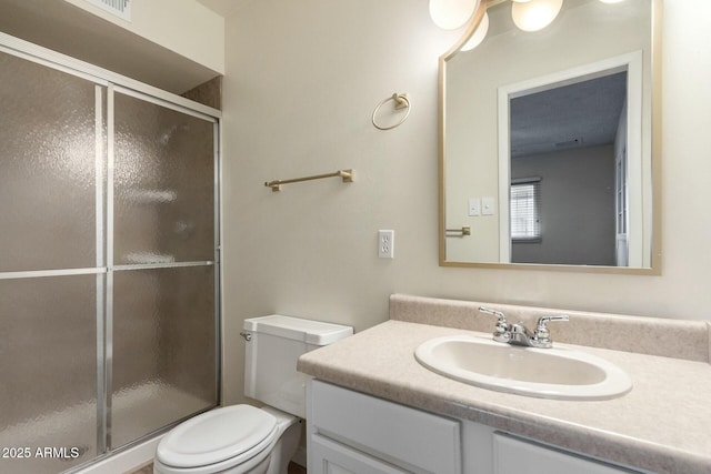 bathroom with toilet, vanity, and a stall shower