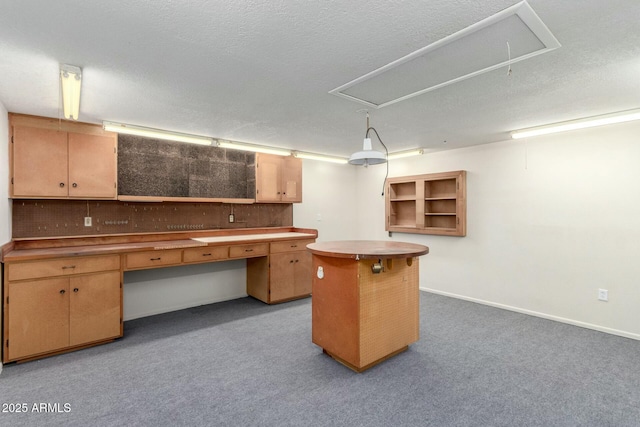 interior space featuring open shelves, a center island, carpet, baseboards, and a textured ceiling