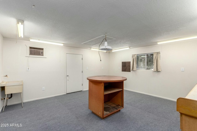 interior space featuring baseboards, a textured ceiling, an AC wall unit, and carpet