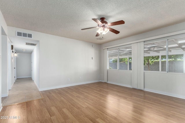 spare room featuring visible vents, light wood-style flooring, and a ceiling fan