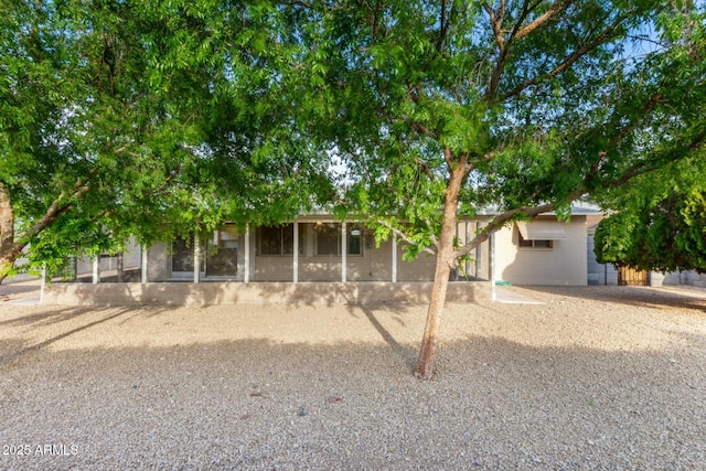 view of property hidden behind natural elements featuring a sunroom