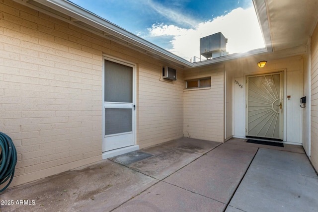 entrance to property with brick siding, central AC unit, and a patio area
