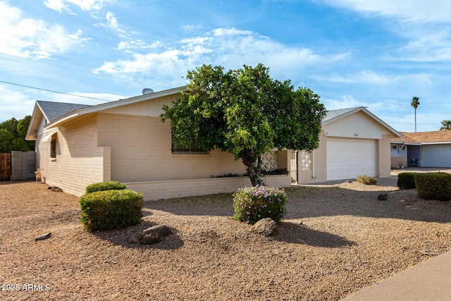 ranch-style home with brick siding, fence, and an attached garage