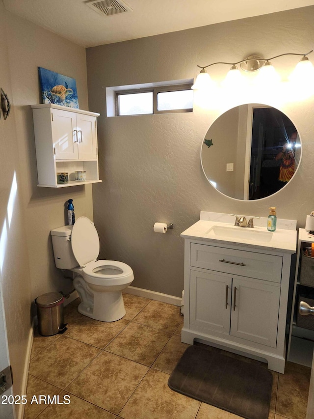 bathroom with toilet, vanity, tile patterned flooring, and baseboards
