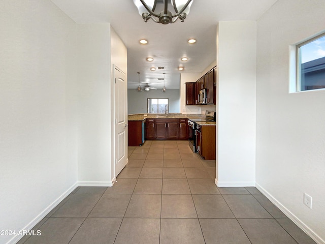 kitchen with stainless steel appliances, a sink, baseboards, tile patterned floors, and an inviting chandelier