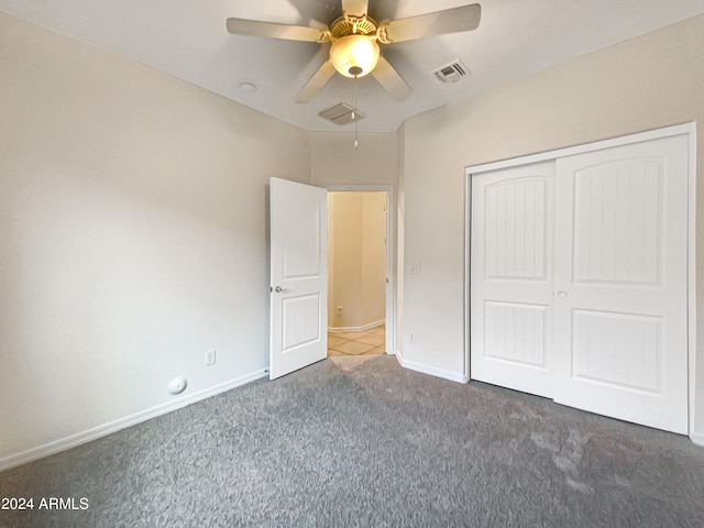 unfurnished bedroom featuring a closet, visible vents, dark carpet, ceiling fan, and baseboards