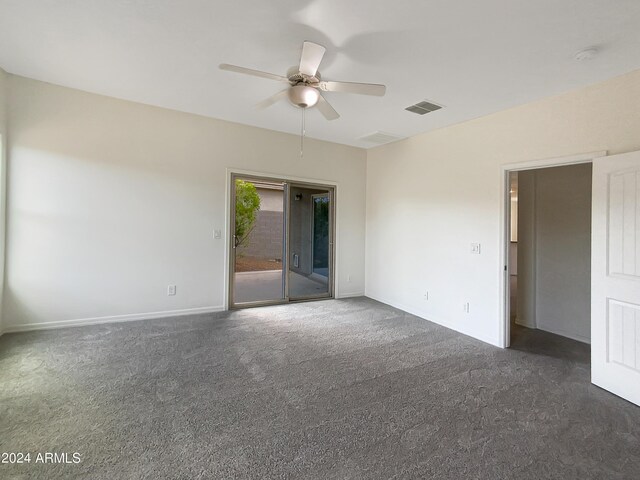 interior space featuring baseboards, visible vents, dark carpet, and a ceiling fan