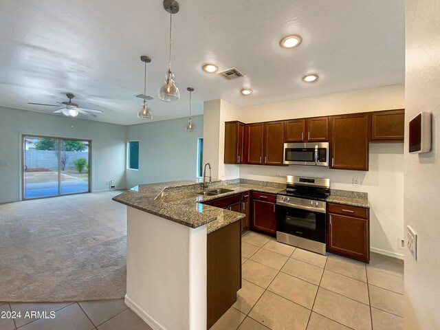 kitchen featuring stainless steel appliances, a peninsula, a sink, open floor plan, and pendant lighting