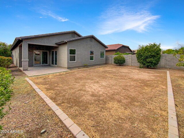 rear view of property featuring a patio area, a fenced backyard, and stucco siding