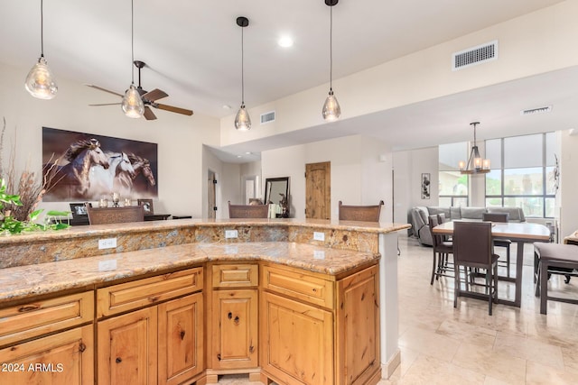 kitchen with ceiling fan with notable chandelier, pendant lighting, and light stone counters