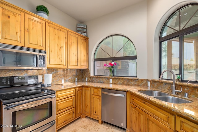 kitchen with light stone countertops, appliances with stainless steel finishes, tasteful backsplash, and sink