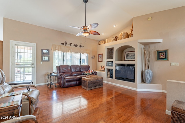 living room with ceiling fan, built in features, hardwood / wood-style floors, and lofted ceiling