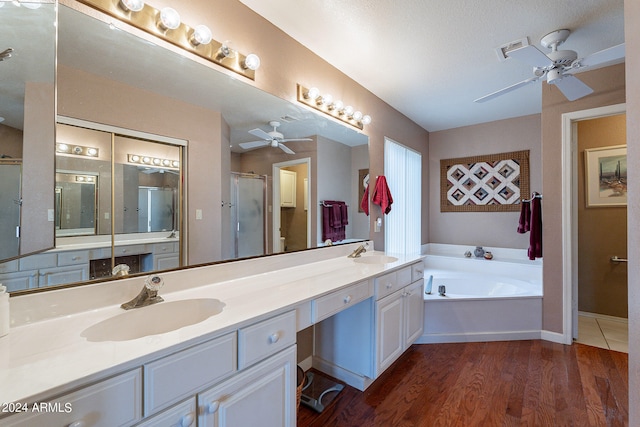 bathroom with a textured ceiling, dual bowl vanity, wood-type flooring, separate shower and tub, and ceiling fan