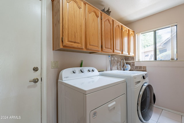 washroom with cabinets, light tile patterned floors, and washer and clothes dryer