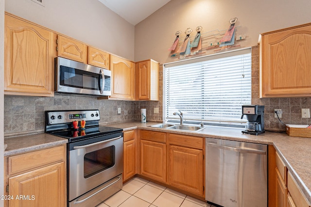 kitchen featuring lofted ceiling, appliances with stainless steel finishes, light tile patterned floors, backsplash, and sink