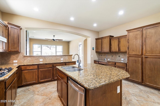 kitchen with arched walkways, stainless steel appliances, backsplash, and a sink