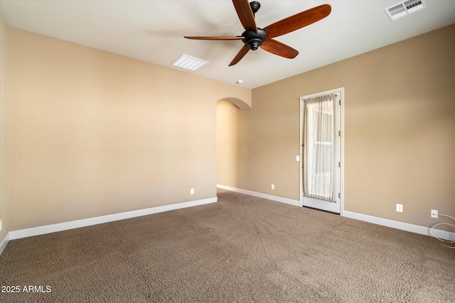 carpeted spare room featuring a ceiling fan, arched walkways, visible vents, and baseboards