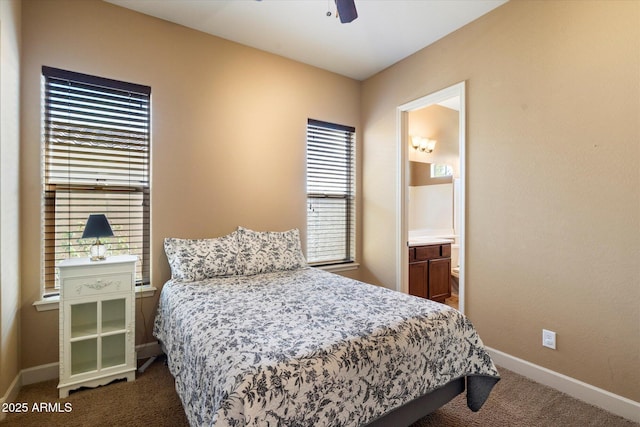 bedroom with dark carpet, connected bathroom, baseboards, and ceiling fan