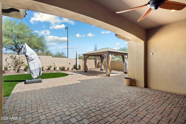 view of patio featuring a gazebo, a fenced backyard, and a ceiling fan