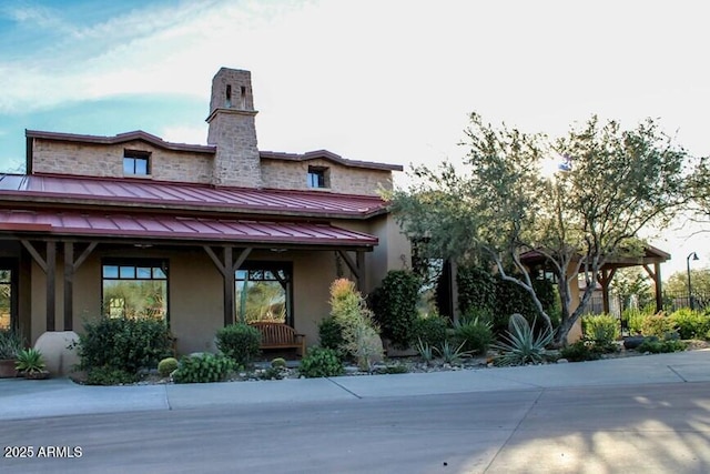 exterior space with a chimney, stucco siding, metal roof, and a standing seam roof