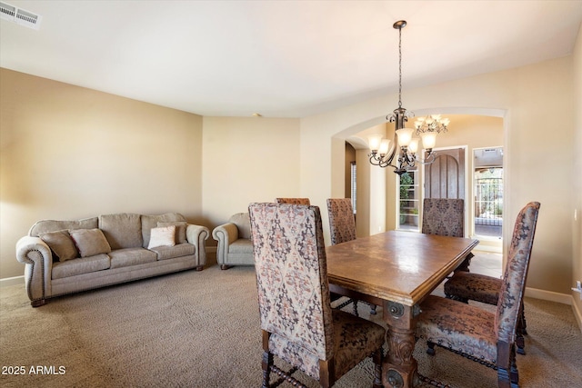 dining space featuring visible vents, carpet floors, baseboards, an inviting chandelier, and arched walkways