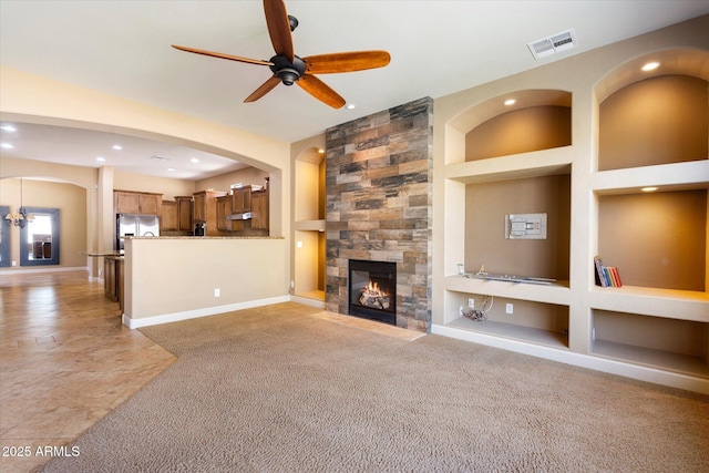 unfurnished living room featuring a tiled fireplace, built in shelves, baseboards, and visible vents