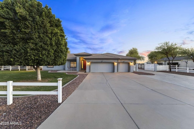 view of front of property with stucco siding, fence, a front lawn, an attached garage, and driveway