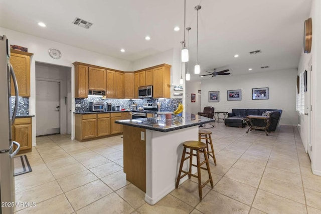 kitchen with open floor plan, a kitchen breakfast bar, visible vents, and stainless steel appliances
