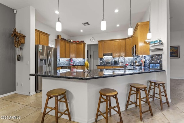 kitchen featuring a peninsula, backsplash, visible vents, stainless steel appliances, and a sink