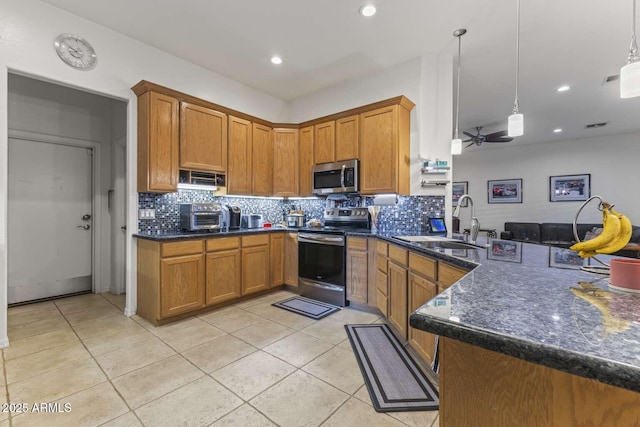 kitchen featuring light tile patterned floors, tasteful backsplash, a sink, stainless steel appliances, and brown cabinets