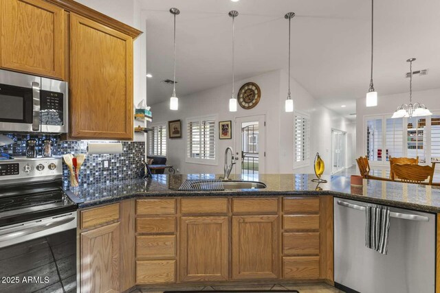 kitchen with brown cabinets, decorative backsplash, a sink, and stainless steel appliances