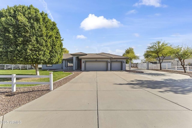 view of front of home with stucco siding, fence, a tile roof, an attached garage, and driveway