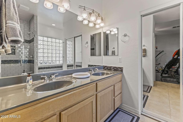 full bathroom featuring tile patterned floors, double vanity, a sink, and tiled shower
