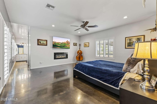 bedroom with finished concrete flooring, a glass covered fireplace, visible vents, recessed lighting, and baseboards