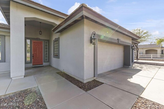 doorway to property featuring concrete driveway, stucco siding, and a garage