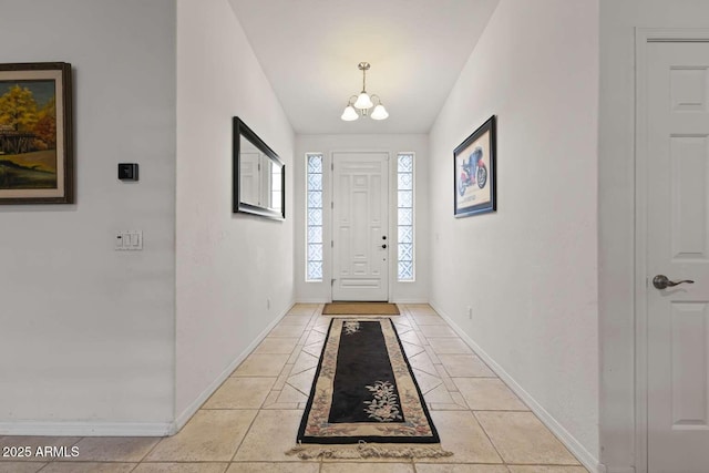 entrance foyer featuring baseboards, an inviting chandelier, and light tile patterned flooring