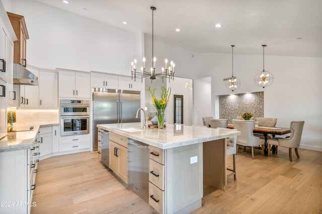 kitchen with appliances with stainless steel finishes, an island with sink, white cabinetry, pendant lighting, and high vaulted ceiling