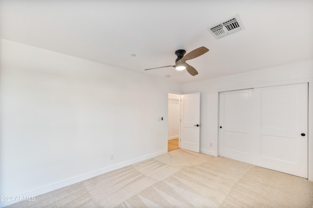 unfurnished bedroom with a closet, light colored carpet, and ceiling fan