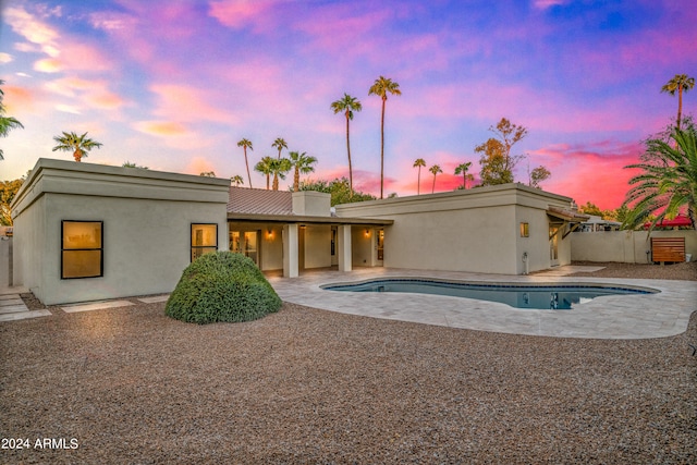 back house at dusk featuring a patio