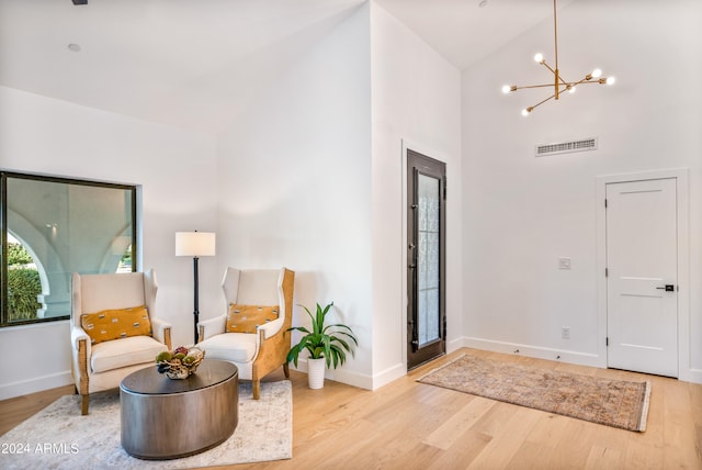 foyer with light hardwood / wood-style floors, high vaulted ceiling, and a chandelier