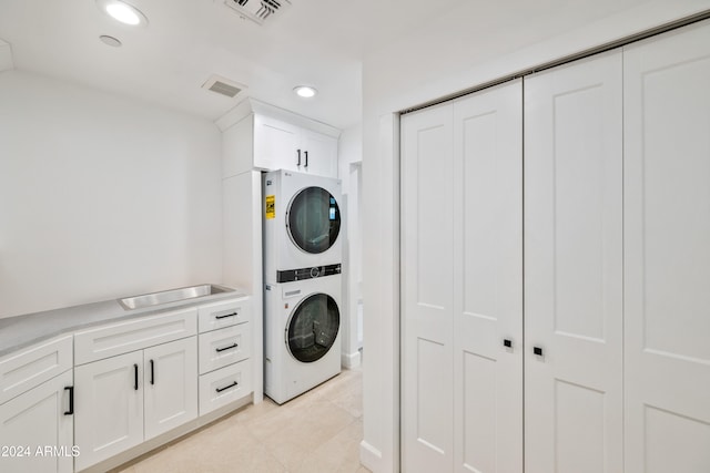 clothes washing area with stacked washer / drying machine and sink