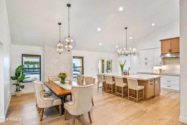 dining area featuring lofted ceiling, a notable chandelier, and light wood-type flooring