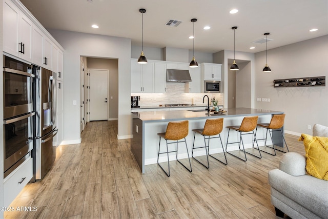 kitchen featuring white cabinetry, hanging light fixtures, and a kitchen island with sink