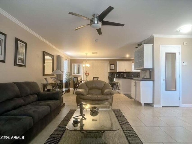 tiled living room with ceiling fan with notable chandelier and crown molding