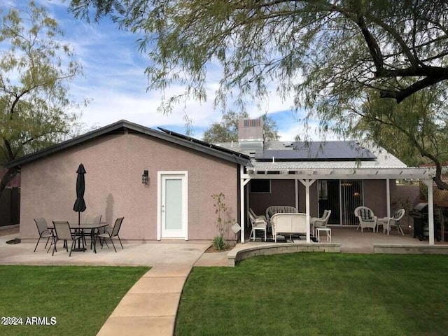 back of house featuring solar panels, a patio area, and a lawn