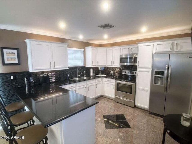 kitchen featuring white cabinets, a kitchen breakfast bar, kitchen peninsula, and stainless steel appliances