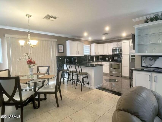 kitchen with backsplash, white cabinets, hanging light fixtures, a kitchen bar, and stainless steel appliances