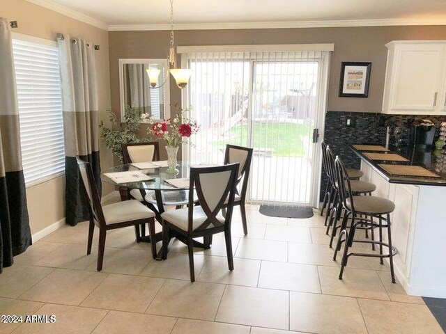 dining area featuring crown molding, light tile patterned flooring, and a notable chandelier