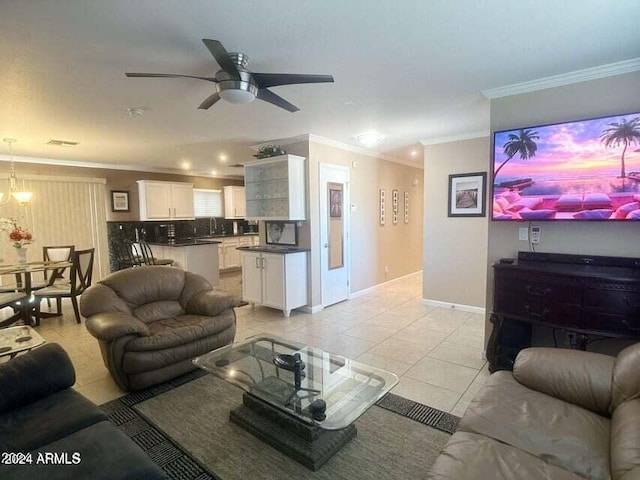 living room with ceiling fan with notable chandelier, ornamental molding, sink, and light tile patterned floors