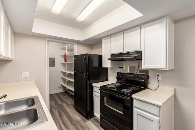 kitchen featuring white cabinetry, a sink, wood finished floors, under cabinet range hood, and black appliances